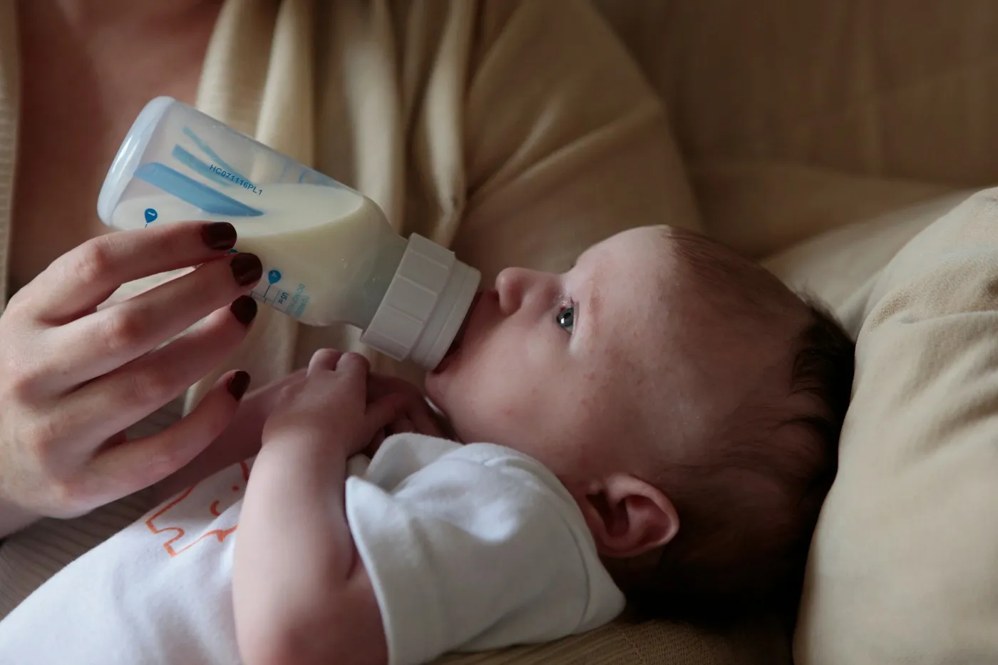A parent bottle feeding a baby